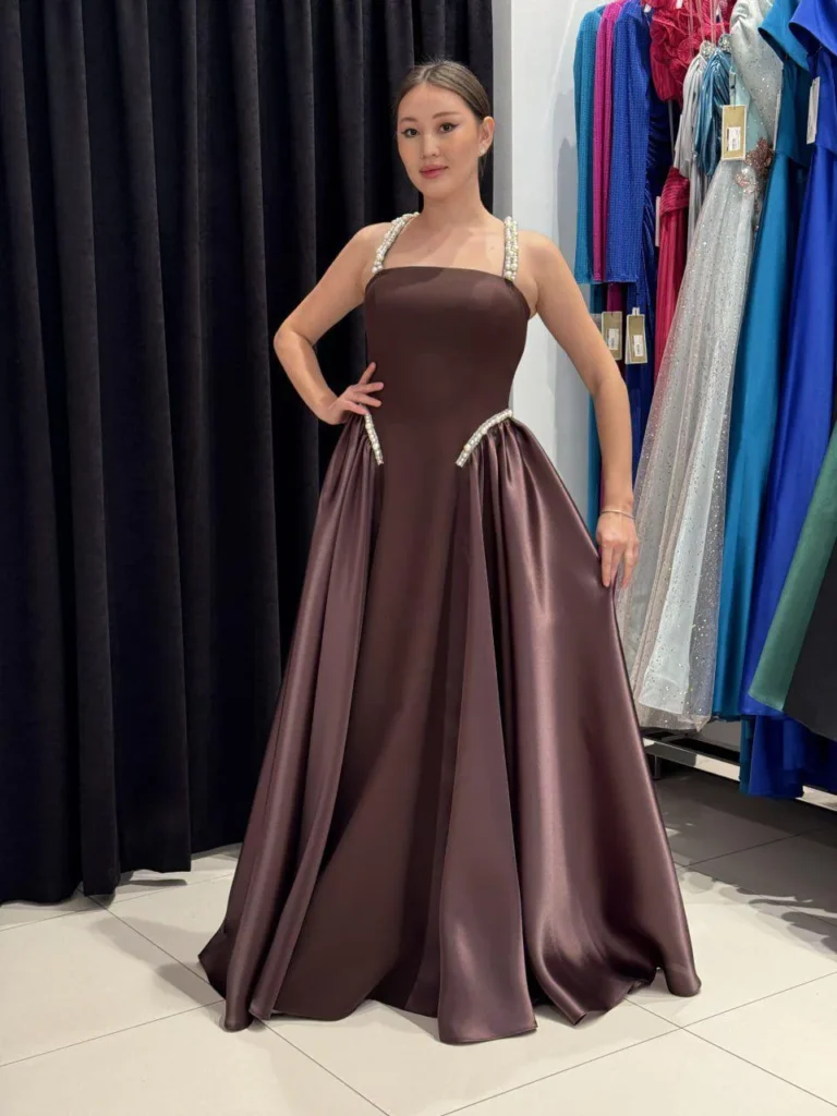 Model wearing a brown evening gown front in store.