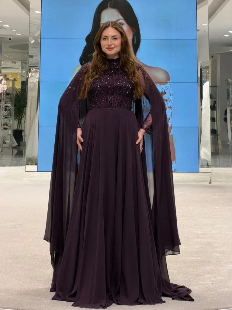 Model wearing a dark purple evening gown in store.