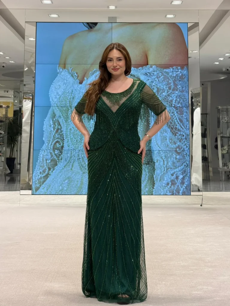 Model wearing a emerald evening gown in store.