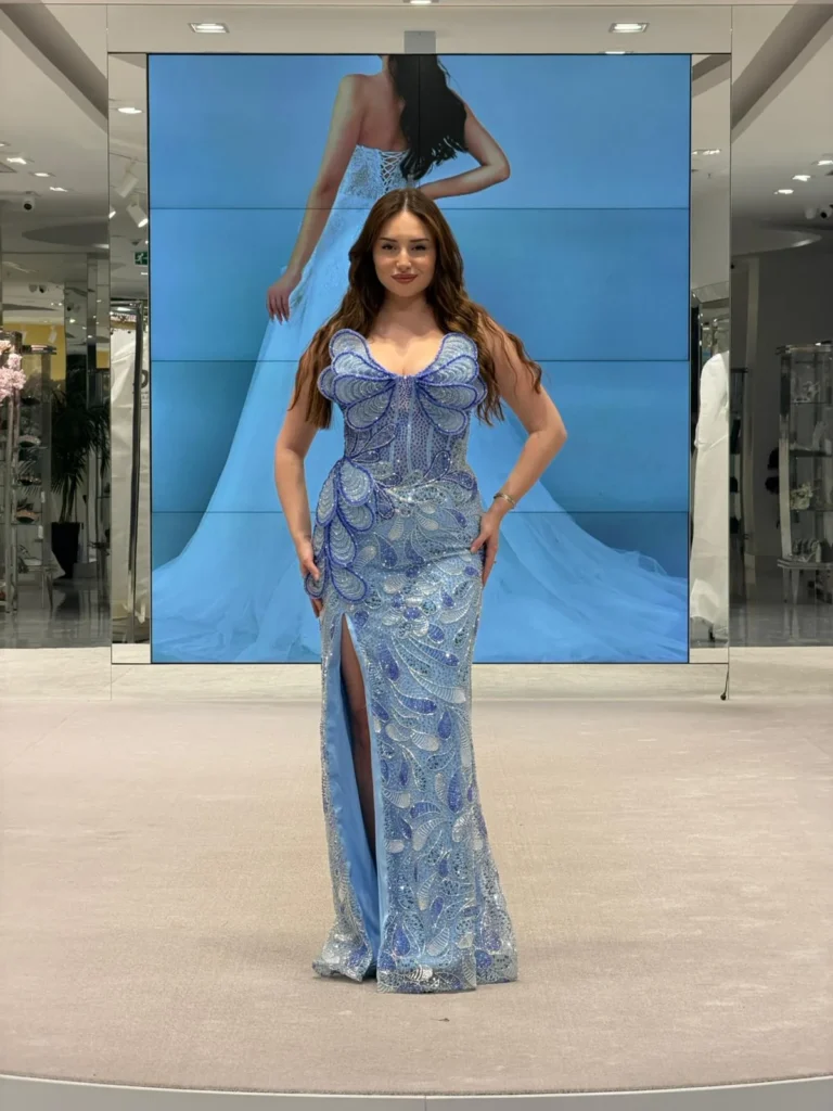 Model wearing a light blue evening gown full length in store.