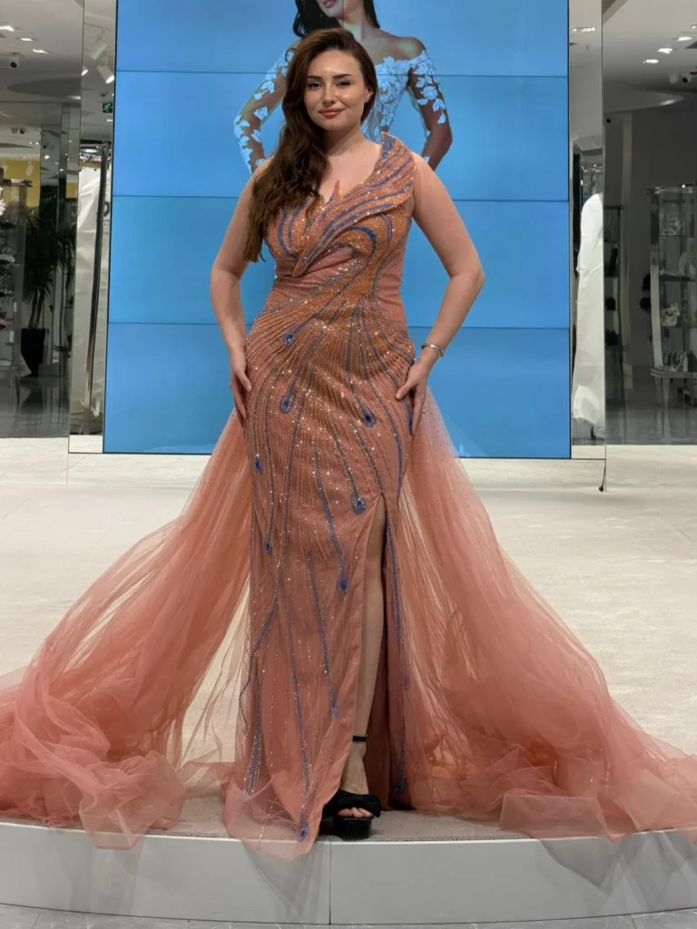 Model wearing a peach evening gown front in store.
